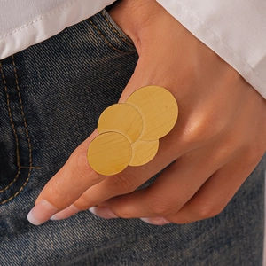 Detail of gold geometric overlapping disc ring with brushed metal texture on denim