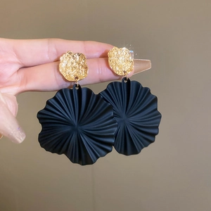 Detailansicht der übergroßen schwarzen Blumenohrringe mit goldfarbenen Metallscheiben