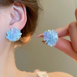 Detail of floral resin stud earrings featuring light blue and purple gradient petals