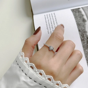 Detail of a vintage 925 silver beaded heart ring worn on a finger over a book