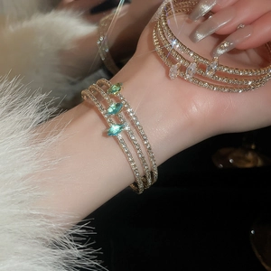 Detail of multi-layer gold bracelet with marquise-cut green stones and pavé set zircons