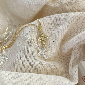 925 silver cross necklace with gold and silver finishes on textured linen background