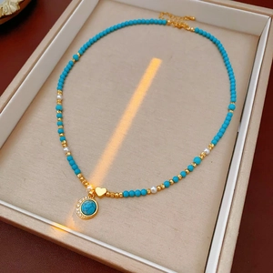 Détail d'un collier de perles turquoise avec breloque cœur doré en boîte à bijoux