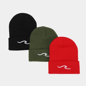 Three knitted beanies in black, green, and red with white wave embroidery on a grey background