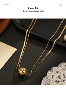 Close-up of gold plated double layer snake chain and bead necklace with ball pendant