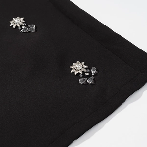 Gros plan détaillé des broderies de cristaux et strass sur le tissu noir élégant