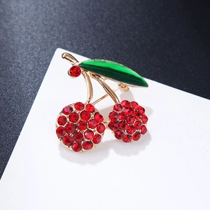 Detailed view of cherry brooch with red rhinestones and green enamel leaf design