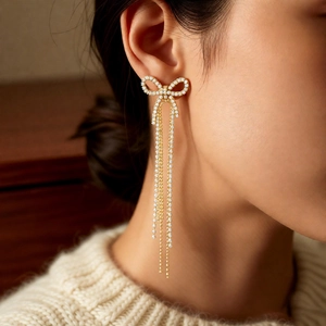 Elegant 18k gold plated bow earrings with long tassels and pearls worn by a female model
