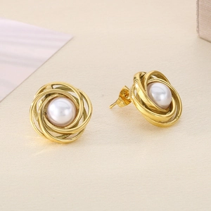Macro shot of gold threaded spiral earrings featuring a central white pearl inlay
