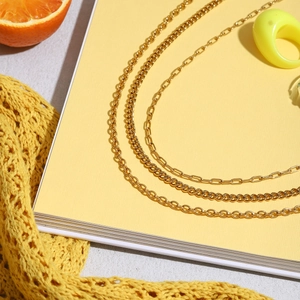 Detalle de collares en capas chapados en oro de 18K con eslabones de clip y marinero planos