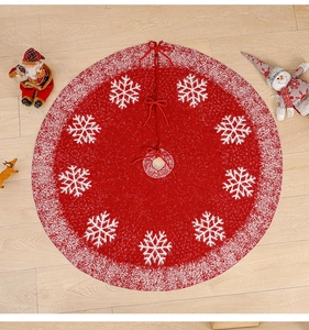 Detail of red knitted Christmas tree skirt with white snowflake patterns and tie closure