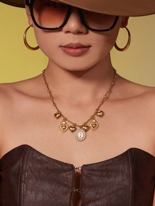 Detail of vintage gold necklace with heart charms and Virgin Mary pendant on model