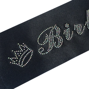 Close-up of black satin sash featuring colorful rhinestones and sparkling crown details