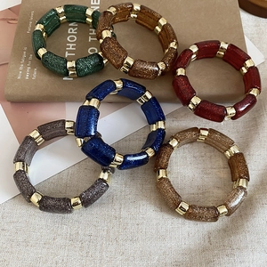 Detail of glitter resin bead bracelets in multiple colors on vintage books background