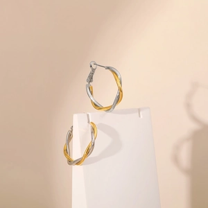 Detail of twisted gold and silver hoop earrings on a professional jewelry display stand