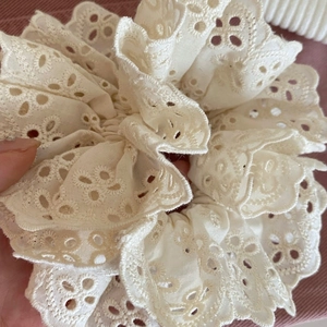 Détail de chouchou en dentelle blanche à double épaisseur avec motifs floraux ajourés chic