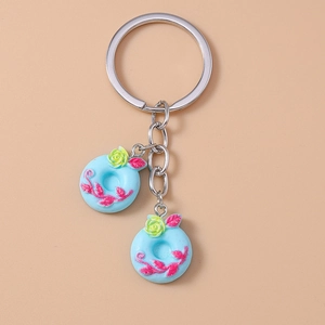 Macro detail of a light blue donut keychain with yellow rose and pink leaf patterns