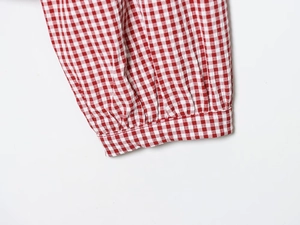 Detail view of red and white gingham shirt cuffs with refined elasticated wrist design