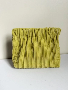 Detail of yellow corduroy cosmetic pouch showing fabric texture and Free Travel label