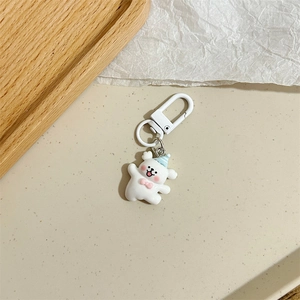 Dettaglio portachiavi a forma di orsetto bianco con cappello da festa e fiocco rosa