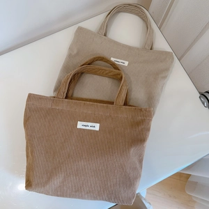 Detail of beige and brown corduroy tote bags with simple wish labels and striped texture