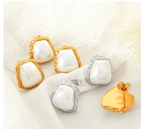 Detailed close-up of textured gold and silver earrings with irregular pearls on lace