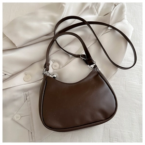 Detail of a dark brown crescent bag with smooth leather texture and silver metal hardware