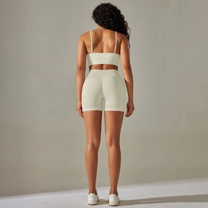 Detail of high-waist seamless yoga shorts and thin strap sports bra set in cream