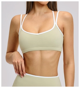 Detail of sage green sports bra with white piping and cross back straps for yoga