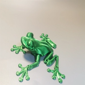 Macro view of a 3D printed green frog model with articulated joints and plastic texture