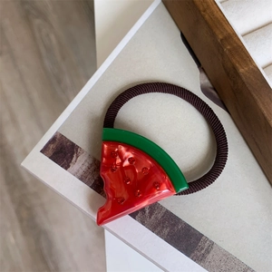 Makro-Detail eines Wassermelonen-Haargummis aus rotem Harz mit funkelnden Strasssteinen