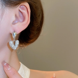 Gros plan de boucles d'oreilles cœur et goutte en zircon portées par un mannequin
