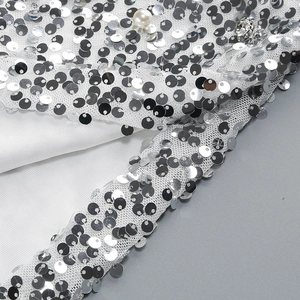 Dettaglio di paillettes argento con perle bianche e strass su tessuto a rete sottile