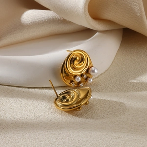 Detailed shot of spiral gold stud earrings with white pearls and sparkling rhinestones