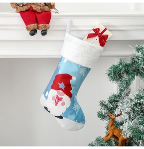 Chaussette de Noël bleue avec motif gnome et boîte cadeau sur une cheminée blanche