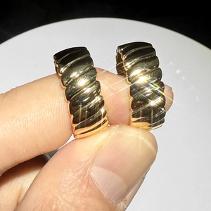 Close-up of golden chunky croissant hoop earrings showing detailed spiral metal texture