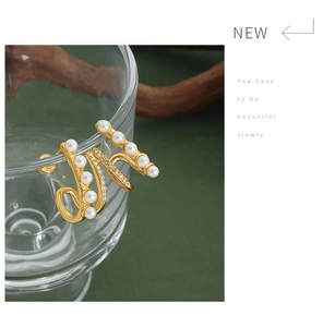 Detail view of double-layered gold titanium earrings with pearls on a glass rim