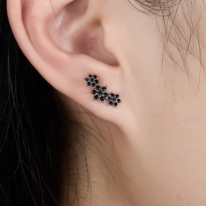 Close-up of elegant black gemstone flower ear climbers worn on a female ear
