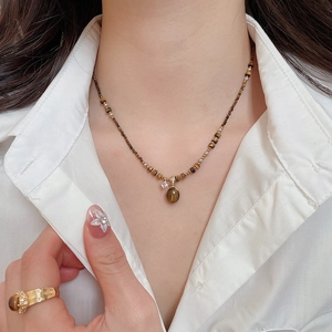 Detail of beaded necklace with tiger eye stone pendant and matching gold ring for women