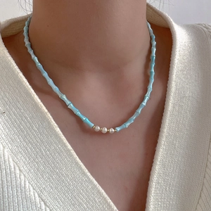 Detail of light blue bamboo-shaped beaded necklace with small white natural pearls