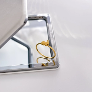 Close-up of golden bunny ring on mirror surface showing polished titanium steel detail