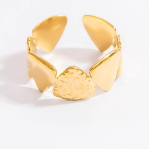 Detailed shot of golden open ring featuring hammered texture and leaf-shaped metal accents