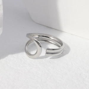 Detail of silver intertwined minimalist stainless steel ring on white geometric stand