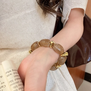Detailed shot of retro oval acrylic beads with golden glitter and metallic spacers on wrist