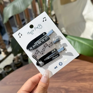 Detailed shot of three music-themed hair clips featuring piano, staff, and guitar designs