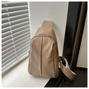 Detailed close-up of beige matte crossbody bag featuring decorative stitching and nylon strap