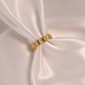 Bague coquillage vintage en acier inoxydable plaqué or 18K sur du tissu satiné blanc