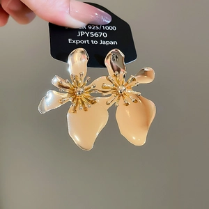 Detail of flower stud earrings featuring cream petals and golden multi-layer metallic stamens