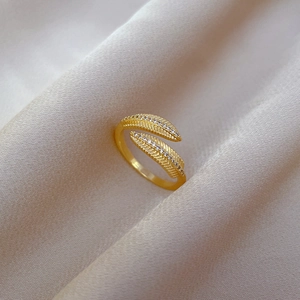 Detail of gold leaf ring with micro-pave white zircon crystals on beige satin fabric