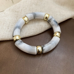 Close-up of marble pattern acrylic beads with golden metal spacers on leather surface